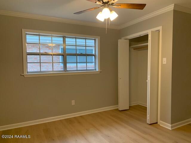 unfurnished bedroom featuring light wood-type flooring, multiple windows, crown molding, and baseboards