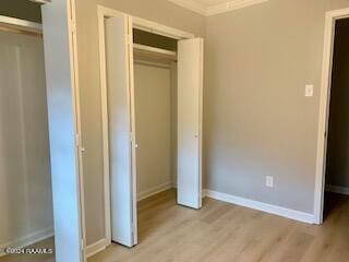 unfurnished bedroom featuring baseboards, a closet, light wood-type flooring, and crown molding