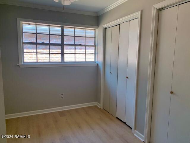 unfurnished bedroom featuring ornamental molding, light wood-style flooring, and baseboards