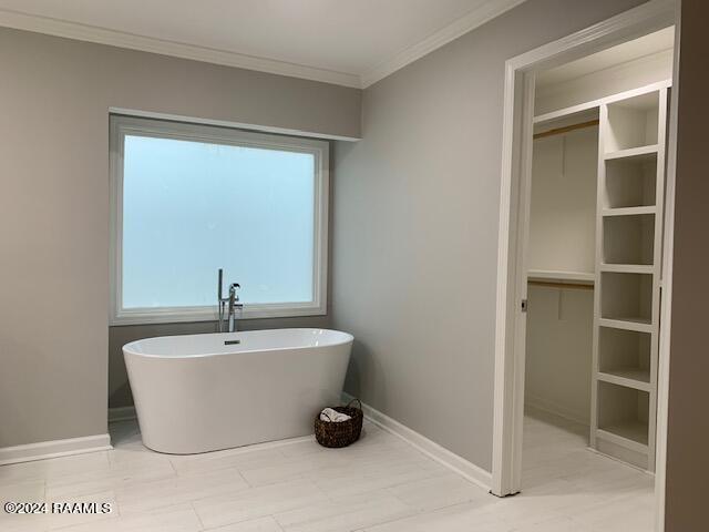 full bathroom featuring a soaking tub, baseboards, a walk in closet, and crown molding