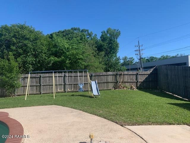 view of yard featuring a fenced backyard, a playground, and a patio