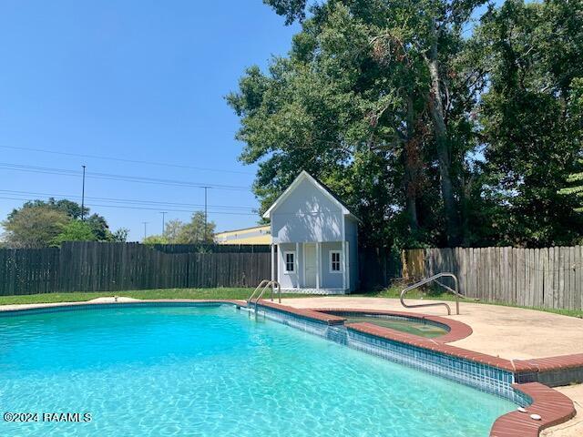 view of pool with a fenced in pool, an outbuilding, a fenced backyard, and an in ground hot tub