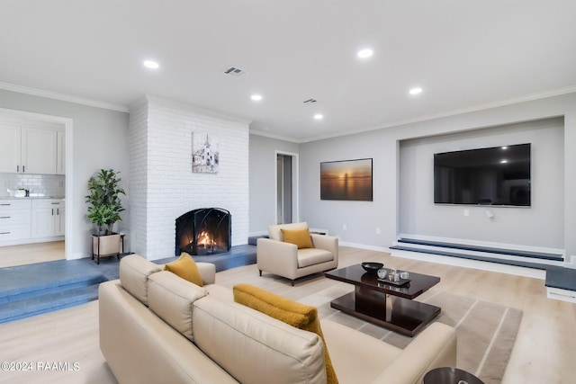 living area featuring crown molding, a fireplace, visible vents, and light wood-style floors