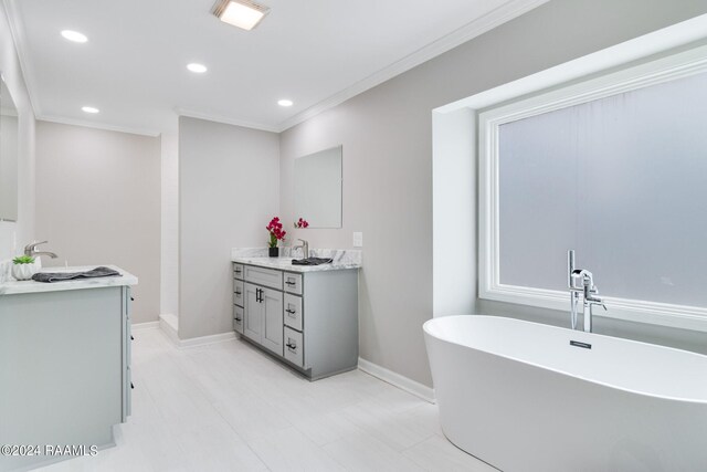 full bath with ornamental molding, a freestanding tub, vanity, and baseboards