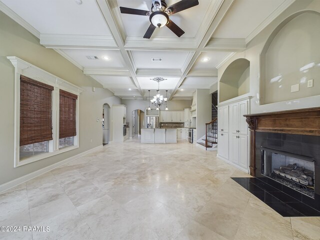 unfurnished living room featuring ceiling fan with notable chandelier, a fireplace, ornamental molding, coffered ceiling, and beam ceiling