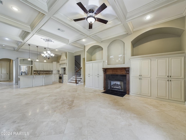 unfurnished living room featuring beamed ceiling, coffered ceiling, ceiling fan with notable chandelier, and crown molding