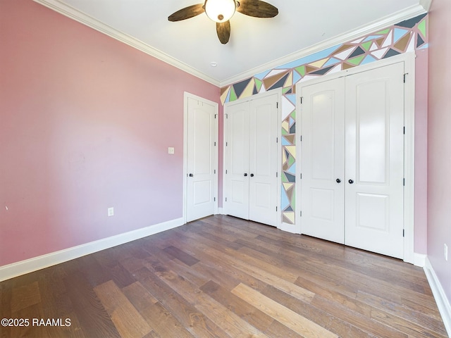 unfurnished bedroom with multiple closets, crown molding, hardwood / wood-style flooring, and ceiling fan