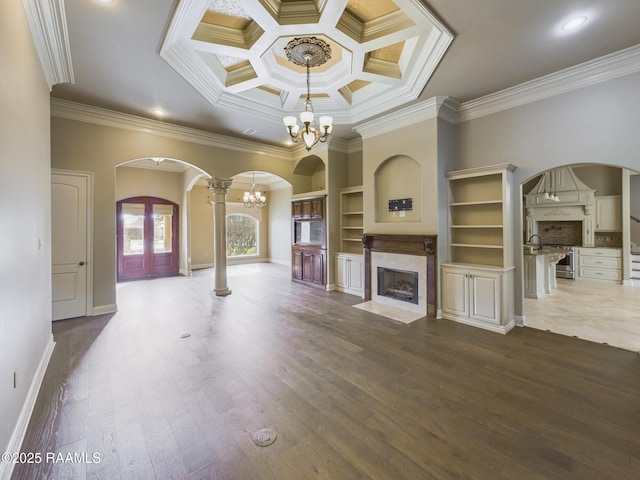 unfurnished living room featuring crown molding, a tile fireplace, dark hardwood / wood-style floors, and a chandelier