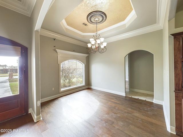 unfurnished dining area featuring an inviting chandelier, dark hardwood / wood-style floors, crown molding, and a raised ceiling