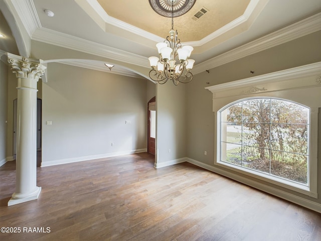 spare room with ornate columns, hardwood / wood-style flooring, and a tray ceiling