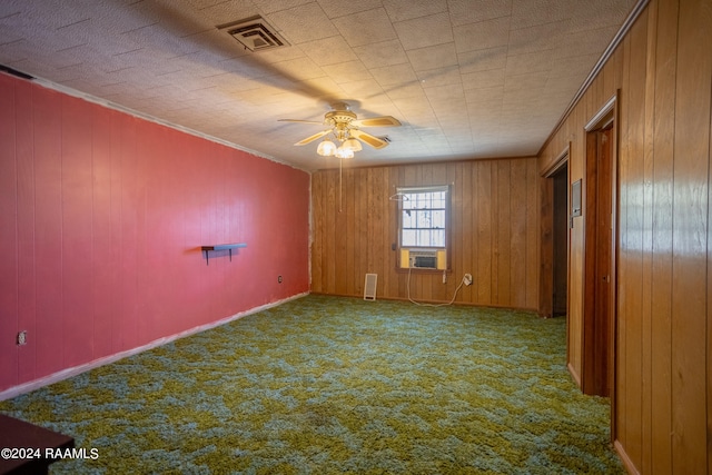 carpeted empty room featuring ceiling fan, wooden walls, and ornamental molding