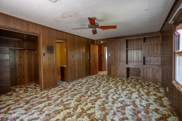 unfurnished bedroom with wooden walls, ceiling fan, light colored carpet, and ornamental molding