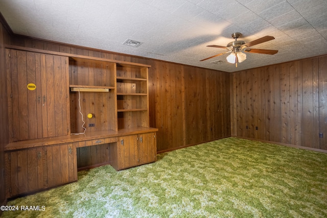 interior space featuring ceiling fan, carpet flooring, and wood walls