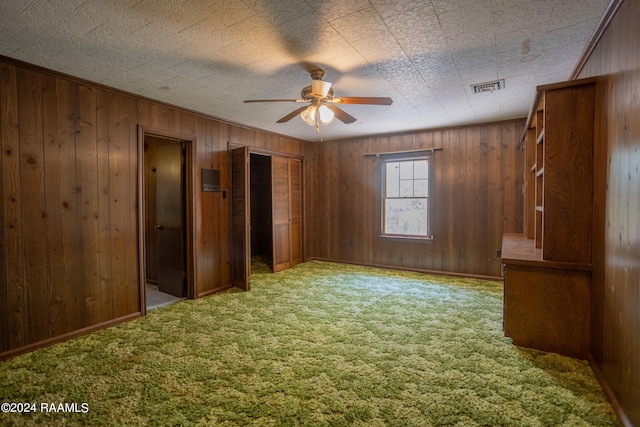 unfurnished room featuring wood walls, ceiling fan, and carpet floors