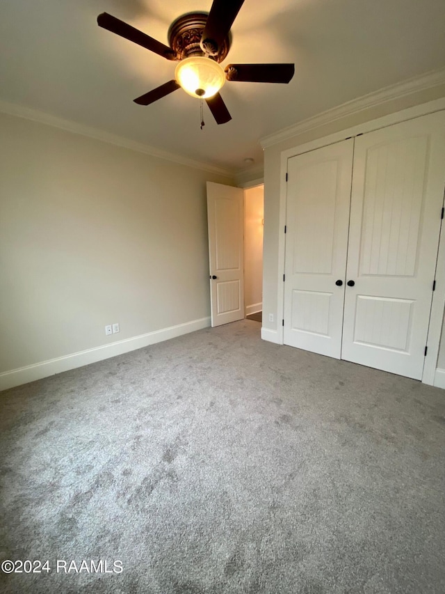 unfurnished bedroom featuring ceiling fan, ornamental molding, light colored carpet, and a closet