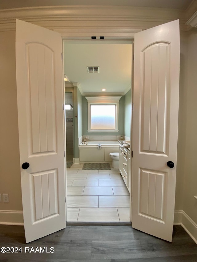 bathroom with toilet, vanity, hardwood / wood-style floors, a bath, and crown molding