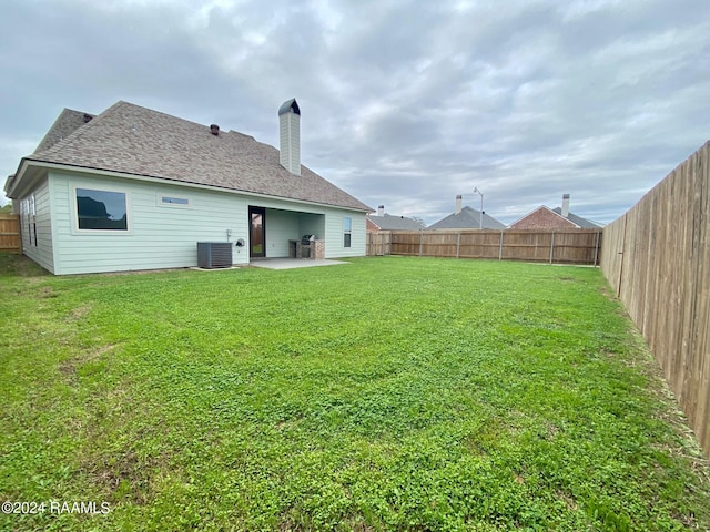 rear view of property featuring a lawn, central AC, and a patio area