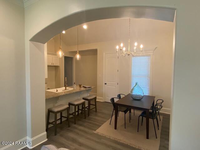 dining space with sink, an inviting chandelier, and dark hardwood / wood-style floors