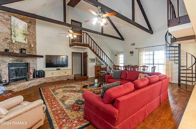 living room with beamed ceiling, wood-type flooring, ceiling fan, a brick fireplace, and high vaulted ceiling