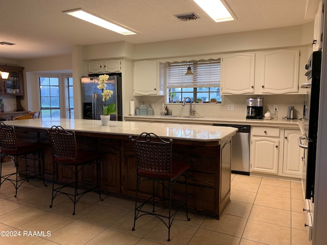 kitchen with appliances with stainless steel finishes, white cabinetry, a healthy amount of sunlight, and sink