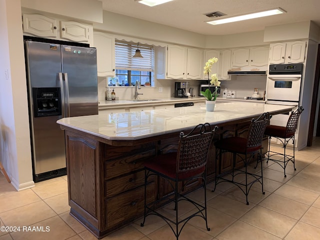 kitchen featuring a kitchen island, light stone counters, appliances with stainless steel finishes, and sink