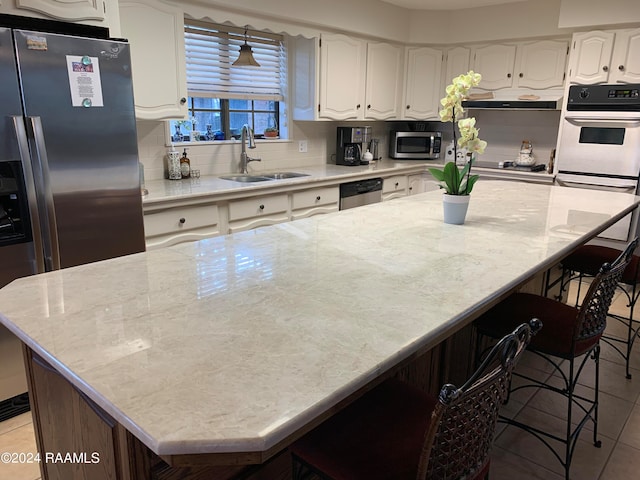 kitchen featuring tasteful backsplash, a center island, stainless steel appliances, sink, and white cabinets