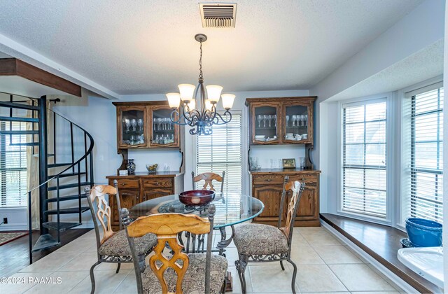 tiled dining room featuring a healthy amount of sunlight, a notable chandelier, and a textured ceiling