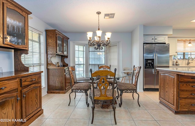 tiled dining room with sink and a notable chandelier