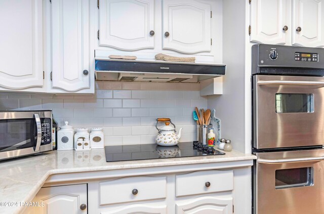 kitchen with backsplash, extractor fan, stainless steel appliances, and white cabinetry