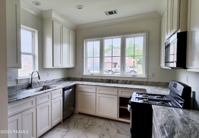 kitchen with a wealth of natural light, light stone counters, sink, and appliances with stainless steel finishes