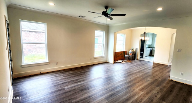 unfurnished living room featuring ceiling fan with notable chandelier, dark hardwood / wood-style flooring, and a wealth of natural light