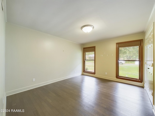 empty room featuring ornamental molding and dark hardwood / wood-style flooring