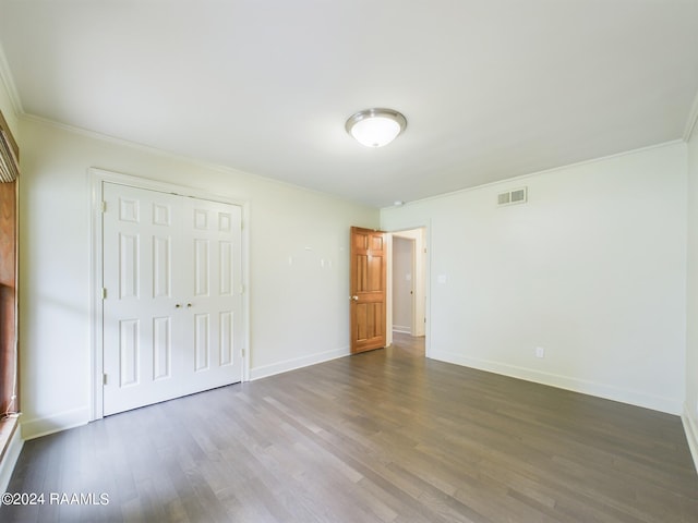 unfurnished bedroom with crown molding, dark hardwood / wood-style floors, and a closet