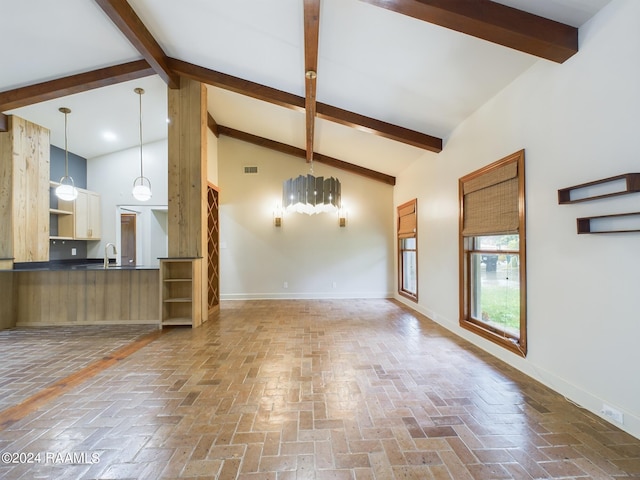 unfurnished living room with beamed ceiling, high vaulted ceiling, and sink