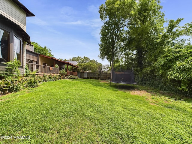 view of yard with a trampoline and a wooden deck