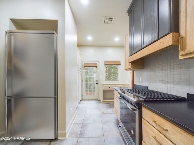 kitchen featuring backsplash, appliances with stainless steel finishes, light tile floors, and light brown cabinetry