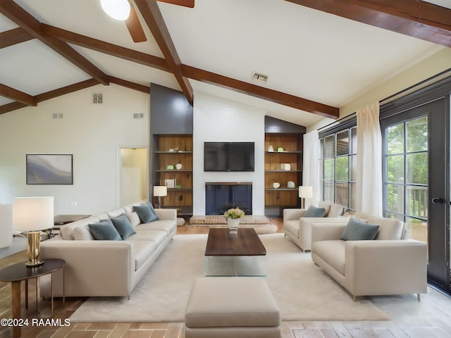 living room with built in features, ceiling fan, beamed ceiling, and a fireplace