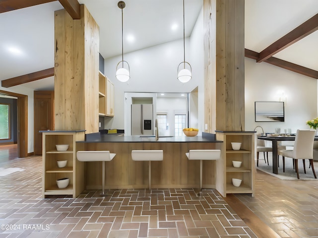 kitchen with high vaulted ceiling, sink, decorative light fixtures, stainless steel fridge with ice dispenser, and kitchen peninsula