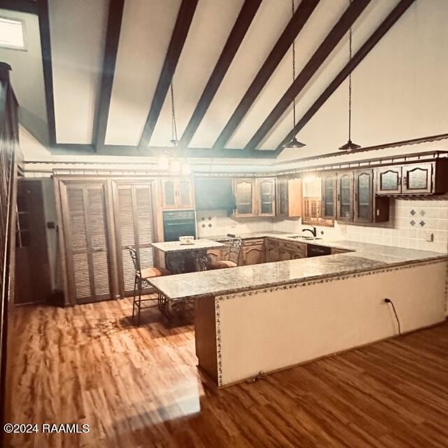 kitchen with sink, light stone counters, kitchen peninsula, pendant lighting, and hardwood / wood-style flooring