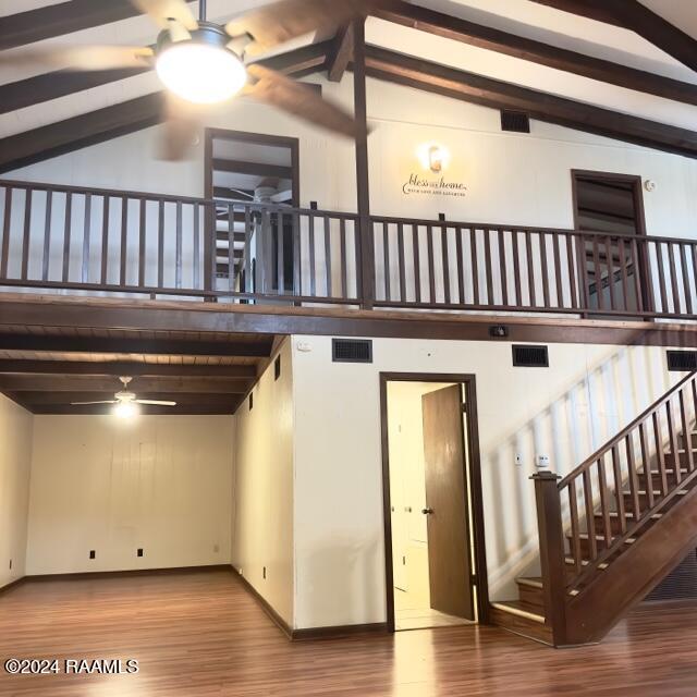 stairway with hardwood / wood-style floors, beamed ceiling, and high vaulted ceiling