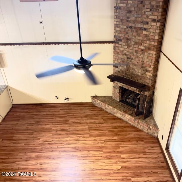 unfurnished living room with light hardwood / wood-style floors, a brick fireplace, and ceiling fan