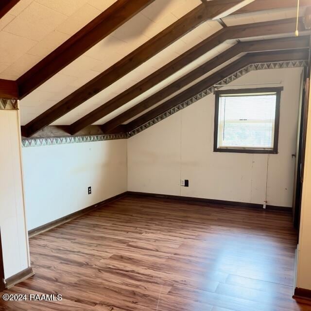 additional living space with hardwood / wood-style floors and lofted ceiling with beams