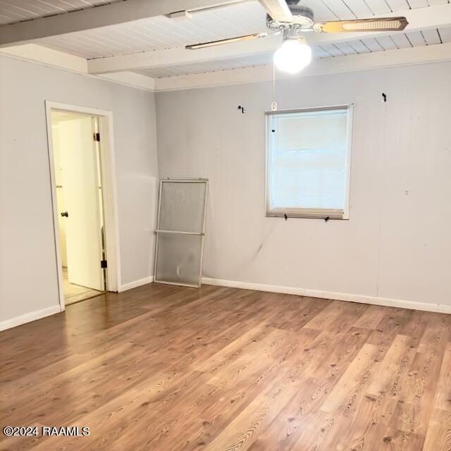 empty room with beam ceiling, wood ceiling, and hardwood / wood-style flooring