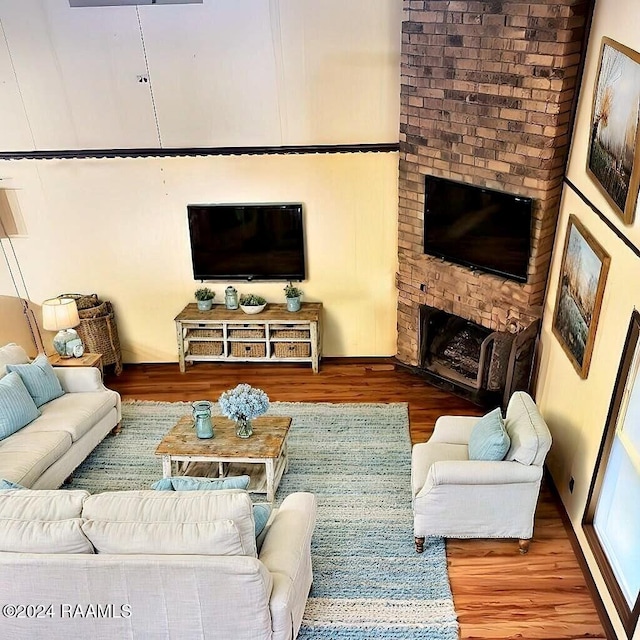 living room featuring wood-type flooring and a brick fireplace