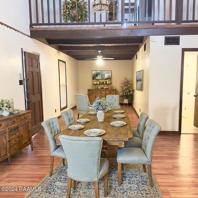 dining room with beam ceiling, ceiling fan with notable chandelier, and hardwood / wood-style flooring