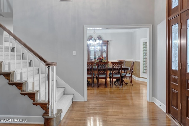 entryway with light hardwood / wood-style flooring, a high ceiling, and a notable chandelier