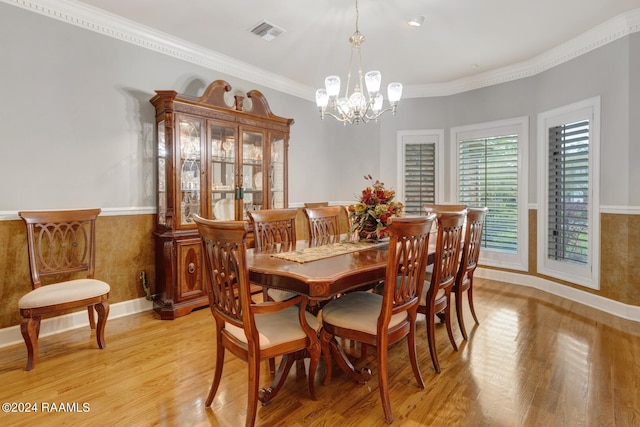 dining area featuring crown molding, a notable chandelier, and light wood-type flooring