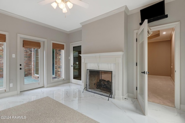 unfurnished living room with a premium fireplace, crown molding, ceiling fan, and light colored carpet