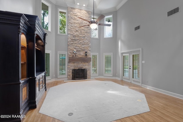 living room featuring light hardwood / wood-style flooring, a healthy amount of sunlight, ceiling fan, and a towering ceiling