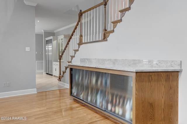 staircase featuring crown molding and light wood-type flooring